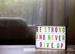 Leuchtschild mit der Aufschrift Be strong and never give up